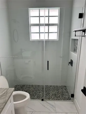 a bathroom with a sink a toilet a window and shower