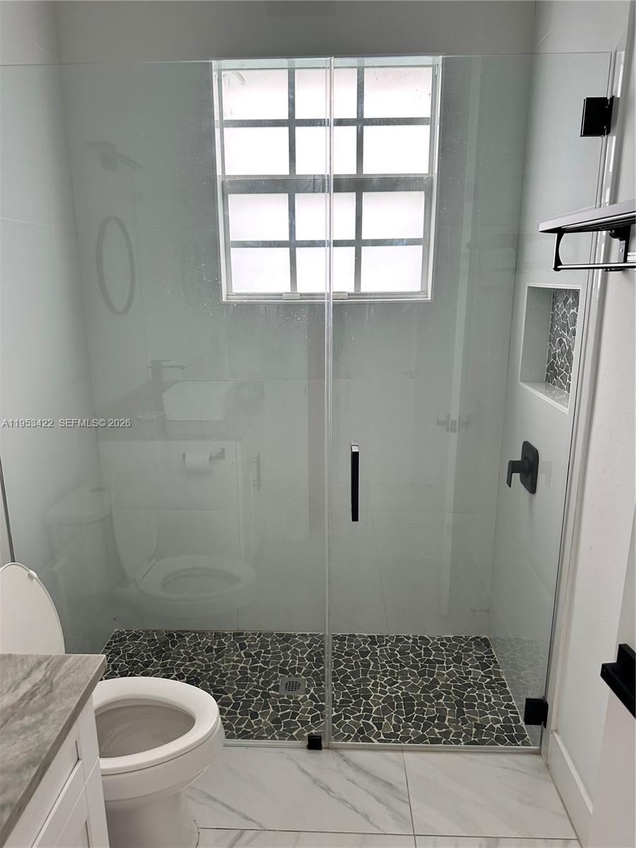 1222 Southwest Herald Road Port St. Lucie, FL 34953 - Photo 18 of 25 a bathroom with a sink a toilet a window and shower