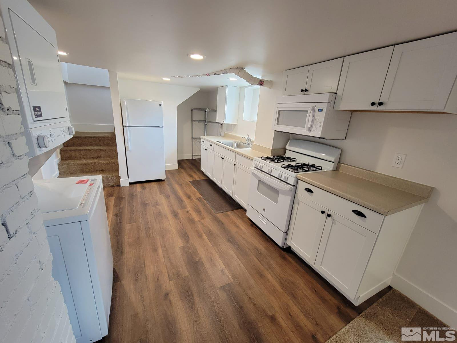 609 West 11th Street Reno, NV 89503 - Photo 23 of 29 a kitchen with stainless steel appliances a stove top oven a refrigerator a sink and white cabinets with wooden floor