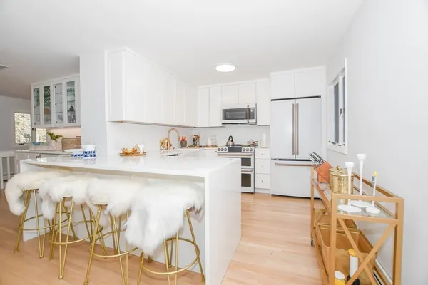 a kitchen with cabinets stainless steel appliances and wooden floor