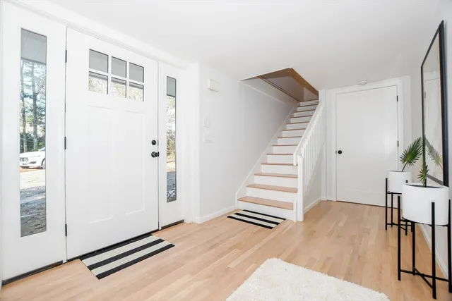 a view of an empty room with wooden floor and stairs