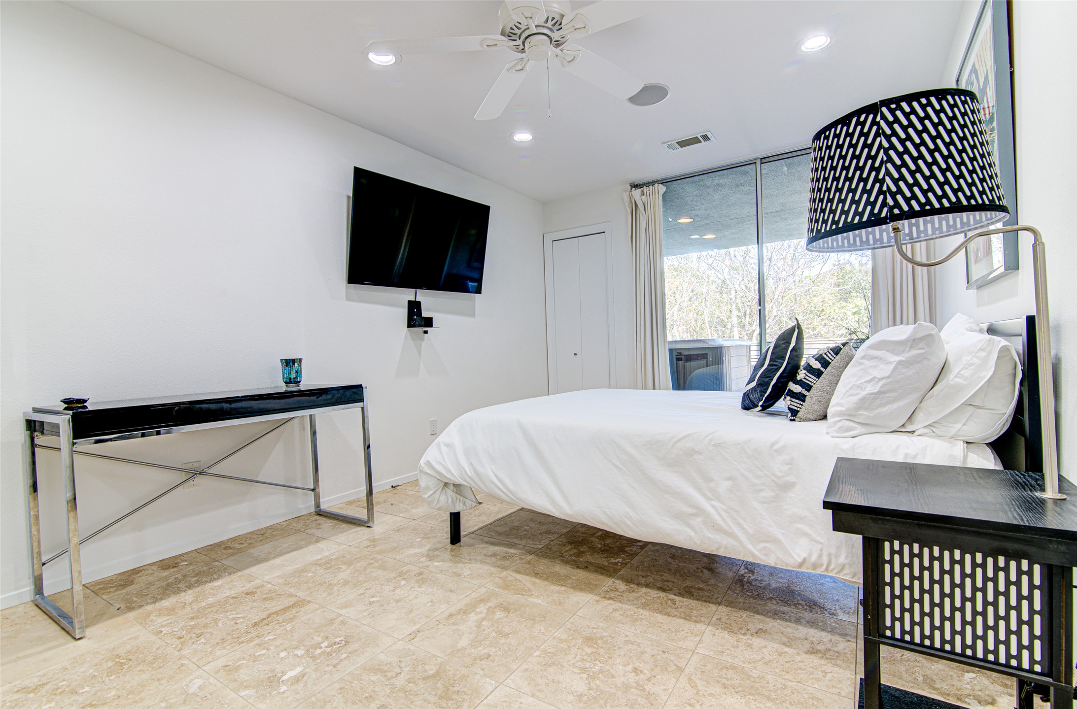 9707 Timber Ridge Pass Austin, TX 78733 - Photo 15 of 18 Polished tile flooring and sliding glass doors enhance this light-filled bedroom retreat.
