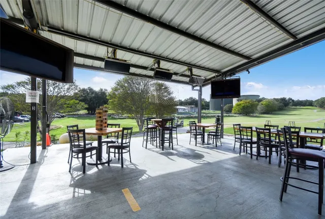 a outdoor space with lots of tables a large window and chairs