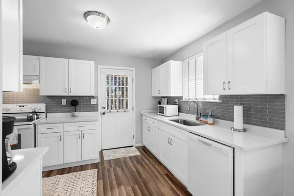 a kitchen with a sink dishwasher stove and white cabinets
