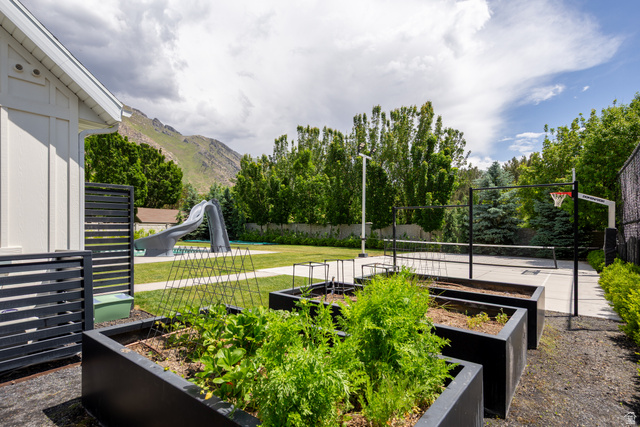 630 East Center Street Alpine, UT 84004 - Photo 94 of 115 Expansive backyard featuring a manicured lawn, an in-ground swimming pool with a slide, a multi-sport court with a basketball hoop and net, and raised garden beds