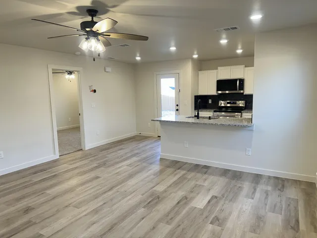 a view of kitchen with stainless steel appliances granite countertop a stove top oven a sink and dishwasher with wooden floor