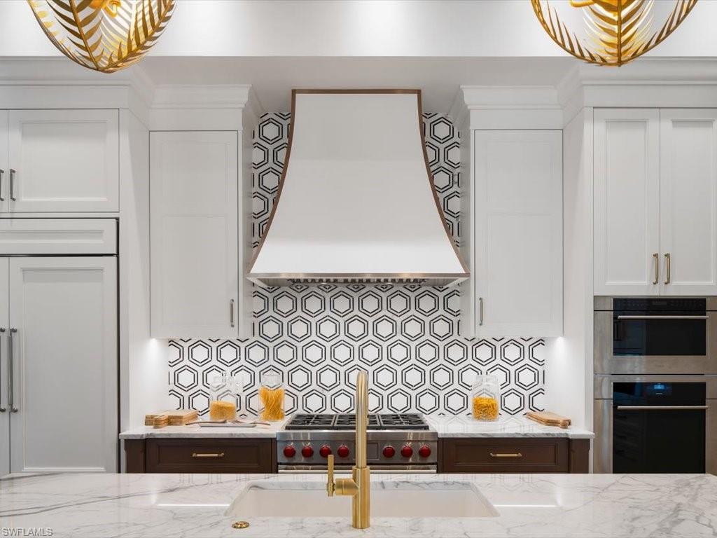 620 Binnacle Drive Naples, FL 34103 - Photo 11 of 49 Kitchen with premium range hood, light stone countertops, stainless steel appliances, and decorative backsplash