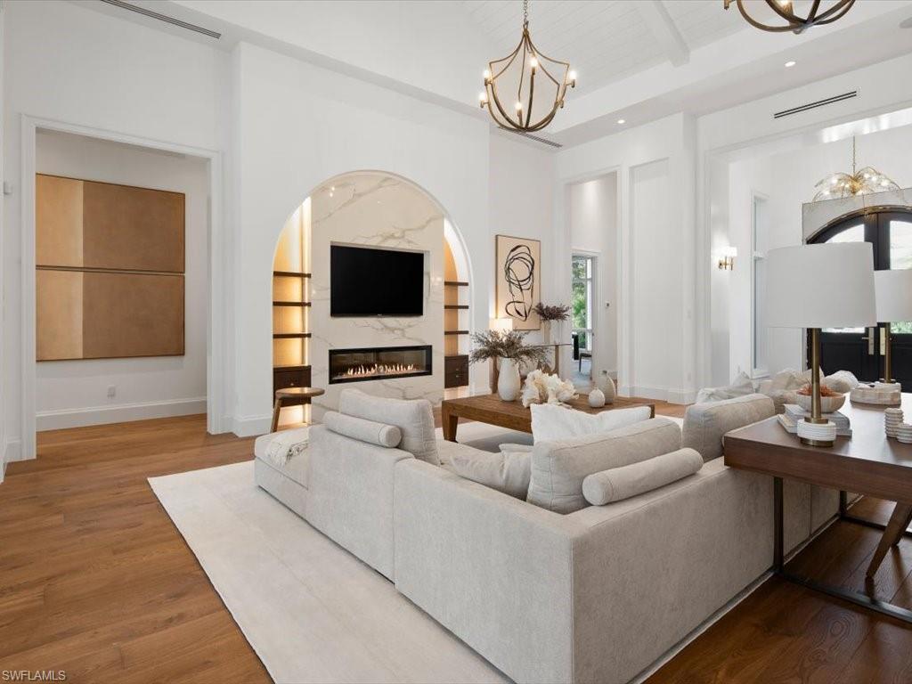 620 Binnacle Drive Naples, FL 34103 - Photo 6 of 49 Living room featuring beamed ceiling, a high end fireplace, a chandelier, a towering ceiling, and hardwood / wood-style floors