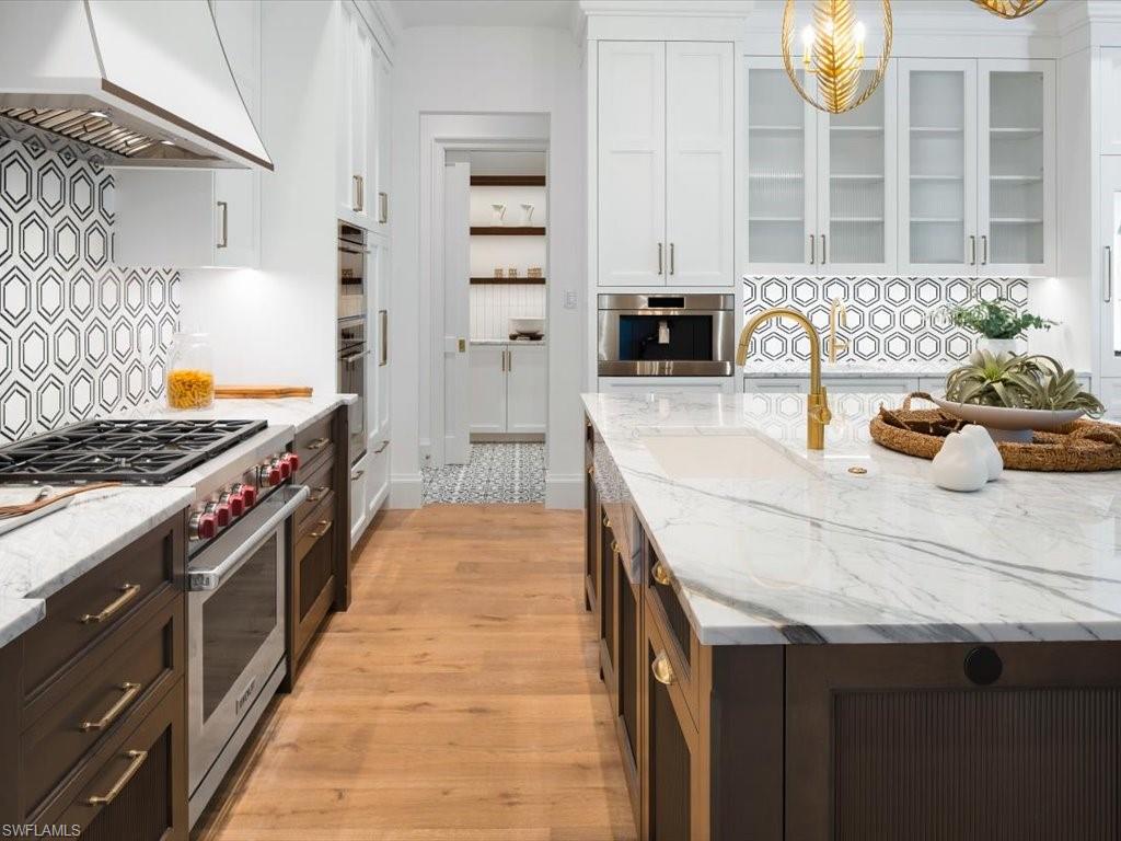 620 Binnacle Drive Naples, FL 34103 - Photo 9 of 49 Kitchen with hanging light fixtures, white cabinetry, appliances with stainless steel finishes, custom range hood, and light hardwood / wood-style floors