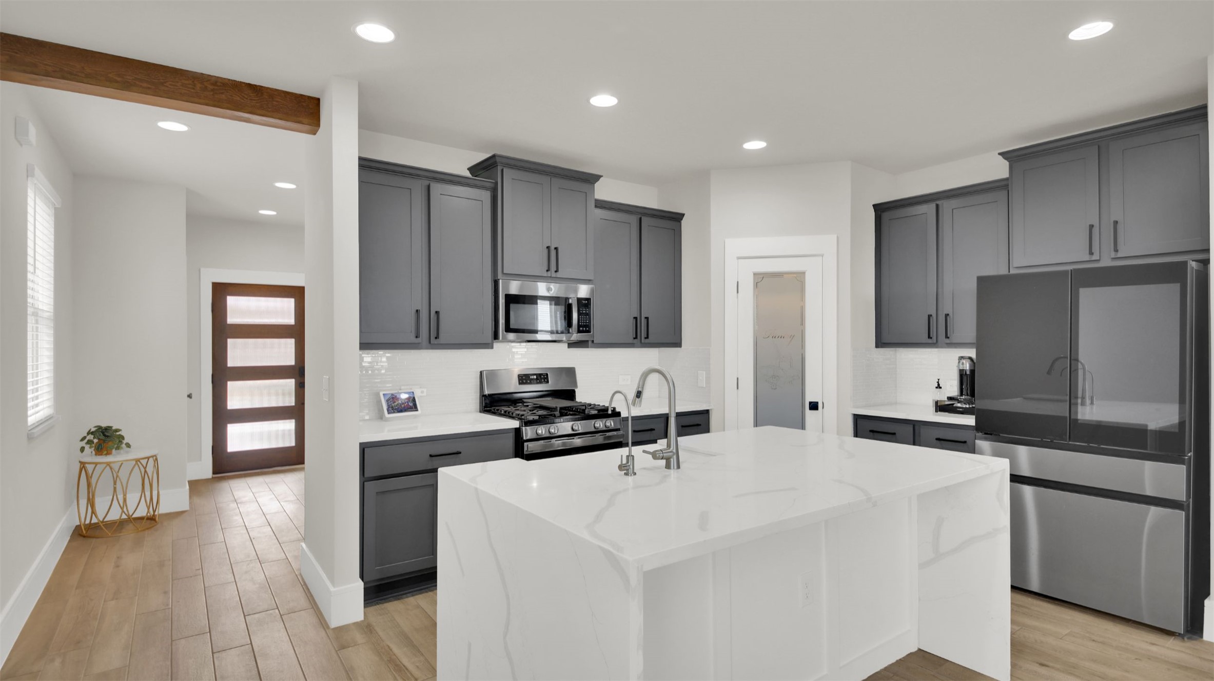 964 Pepperbark Loop Buda, TX 78610 - Photo 1 of 23 Kitchen with stainless steel appliances, decorative backsplash, light stone countertops, light wood-style flooring, and a kitchen island with sink
