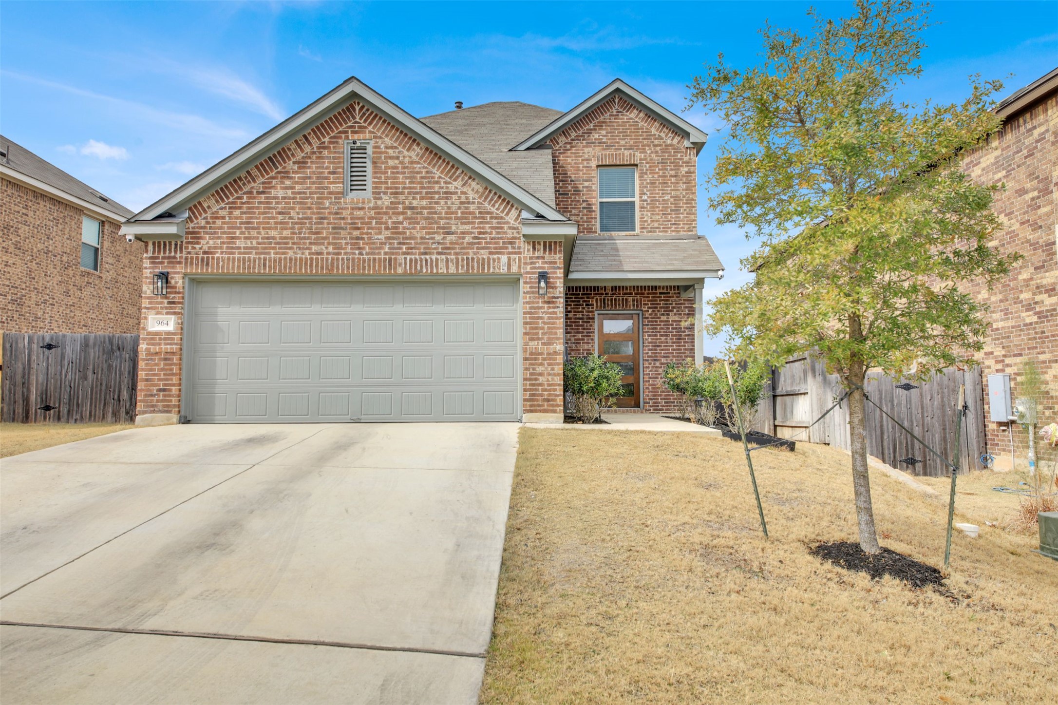 Traditional-style home with brick siding, driveway, an attached garage, and a shingled roof