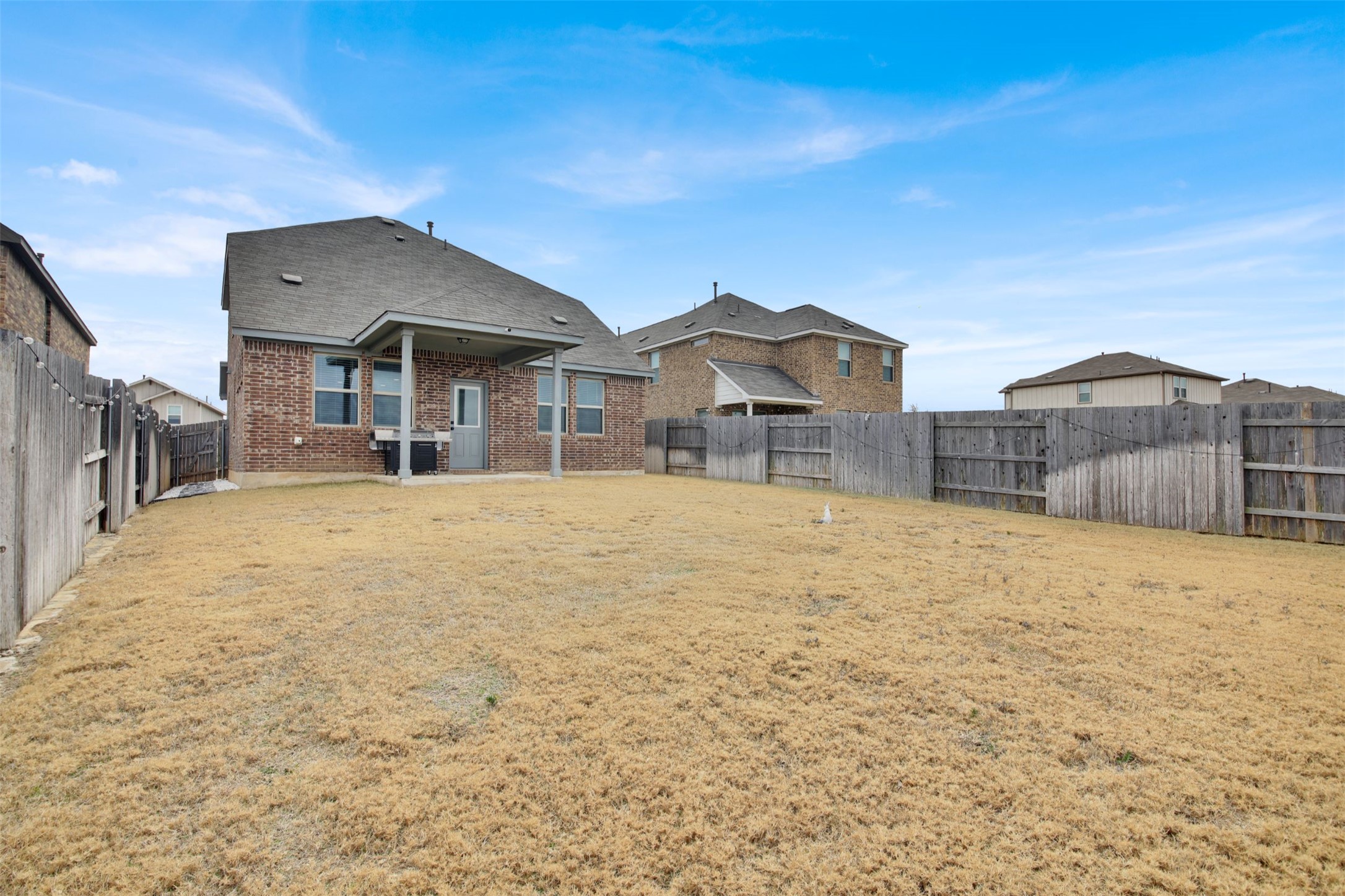 964 Pepperbark Loop Buda, TX 78610 - Photo 30 of 35 Rear view of property featuring a patio, a fenced backyard, and brick siding