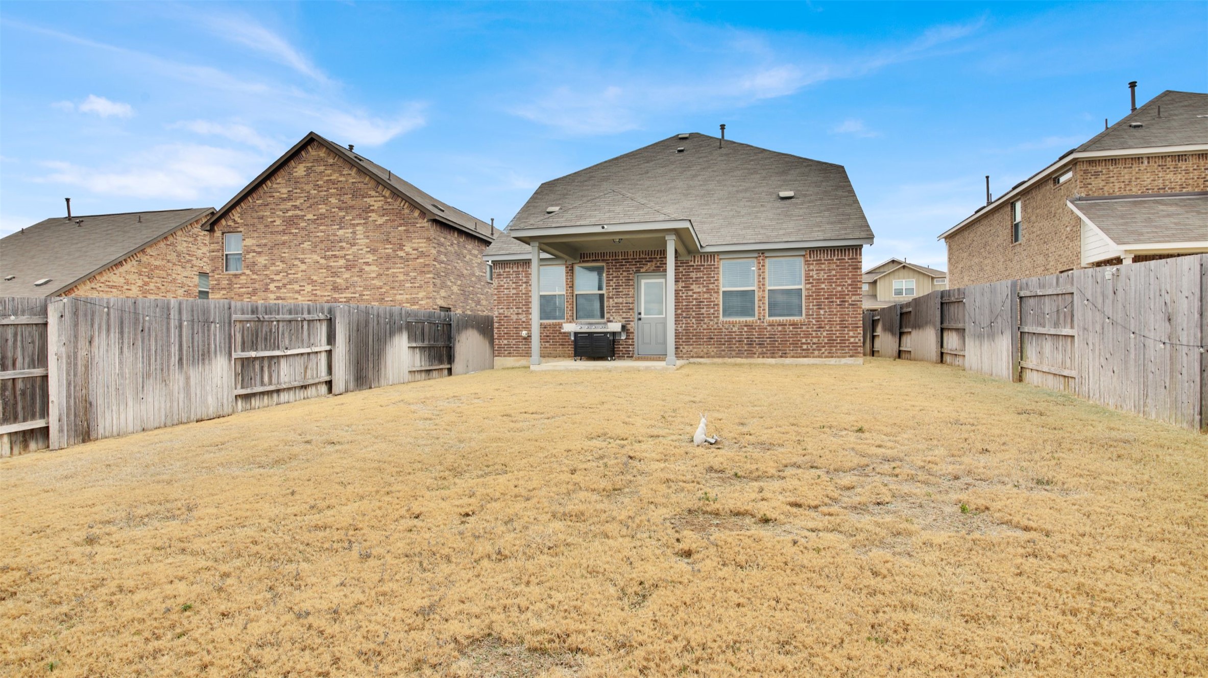 964 Pepperbark Loop Buda, TX 78610 - Photo 32 of 35 Rear view of house with a patio, a fenced backyard, and brick siding