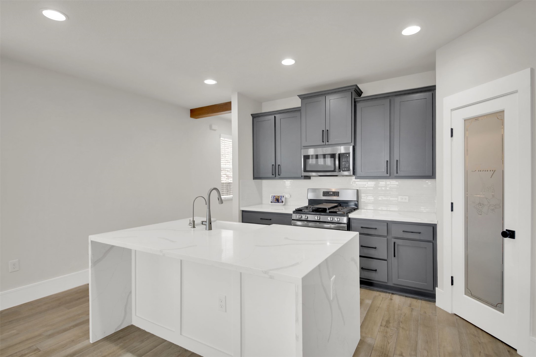 964 Pepperbark Loop Buda, TX 78610 - Photo 9 of 35 Kitchen with stainless steel appliances, light stone countertops, tasteful backsplash, gray cabinetry, and light wood-type flooring