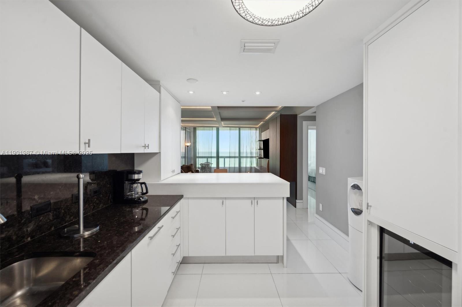 6899 Collins Avenue, Unit 702 Miami Beach, FL 33141 - Photo 11 of 47 a large white kitchen with a sink and cabinets
