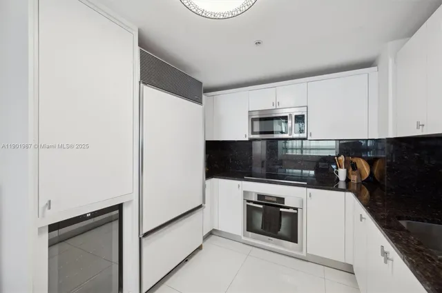 a kitchen with granite countertop white cabinets and stainless steel appliances