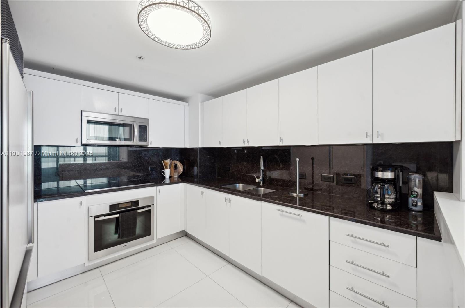 6899 Collins Avenue, Unit 702 Miami Beach, FL 33141 - Photo 14 of 47 a kitchen with granite countertop white cabinets and stainless steel appliances
