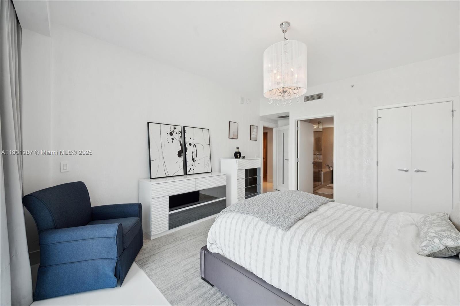 6899 Collins Avenue, Unit 702 Miami Beach, FL 33141 - Photo 17 of 47 a spacious bedroom with a bed chandelier painting on the wall and a window