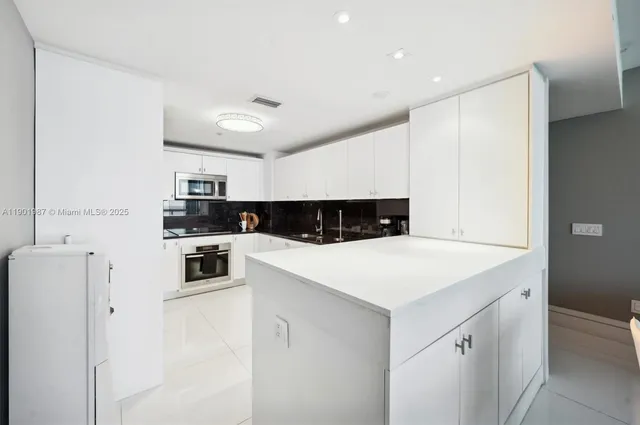 a kitchen with stainless steel appliances granite countertop a sink and a white cabinets