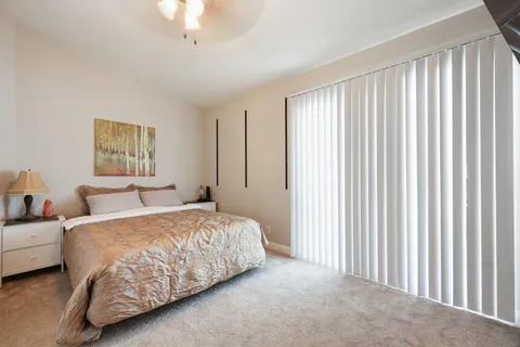 a bedroom with a bed lamp and a large window