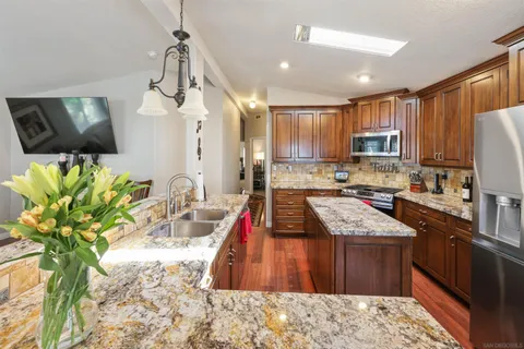 a kitchen with kitchen island granite countertop a sink a counter top space appliances and cabinets