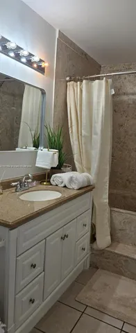 a bathroom with a granite countertop sink a mirror and shower