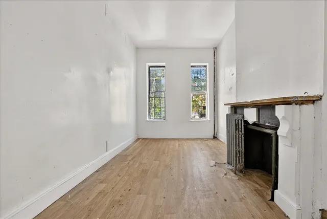 an empty room with wooden floor closet and windows