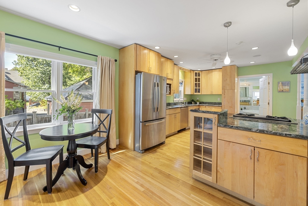 8 Hatch Road Medford, MA 02155 - Photo 16 of 42 a kitchen with stainless steel appliances granite countertop a stove a refrigerator a microwave a dining table and chairs with wooden floor