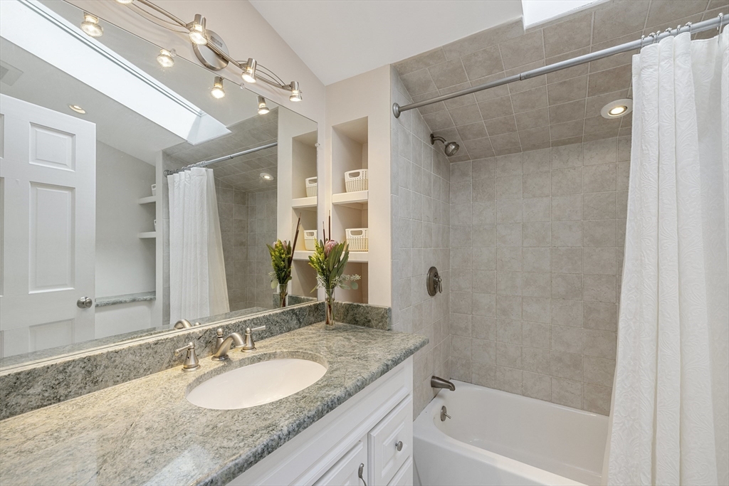 8 Hatch Road Medford, MA 02155 - Photo 24 of 42 a bathroom with a granite countertop sink a mirror a bathtub and shower