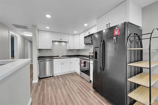a kitchen with a refrigerator and white cabinets