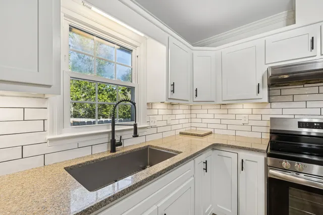 a kitchen with granite countertop white cabinets and sink