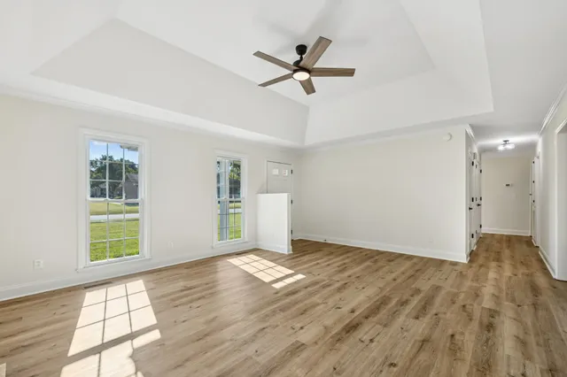 a view of an empty room with wooden floor fireplace and a window
