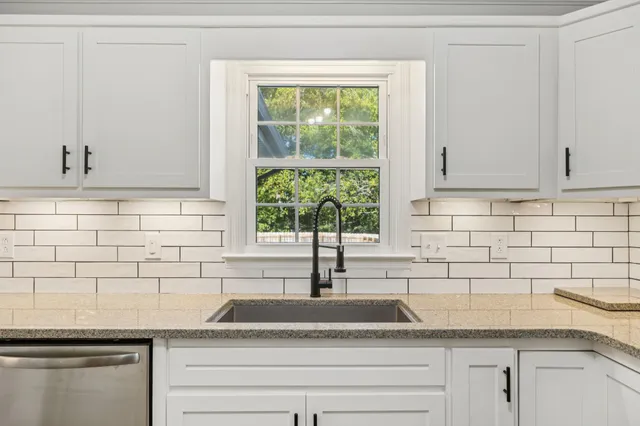 a kitchen with granite countertop white cabinets and a window