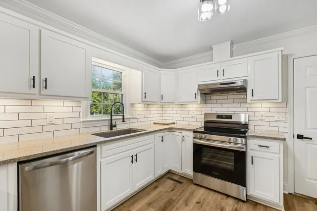a kitchen with cabinets stainless steel appliances a sink and a window