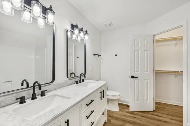 a bathroom with a double vanity sink mirror and toilet