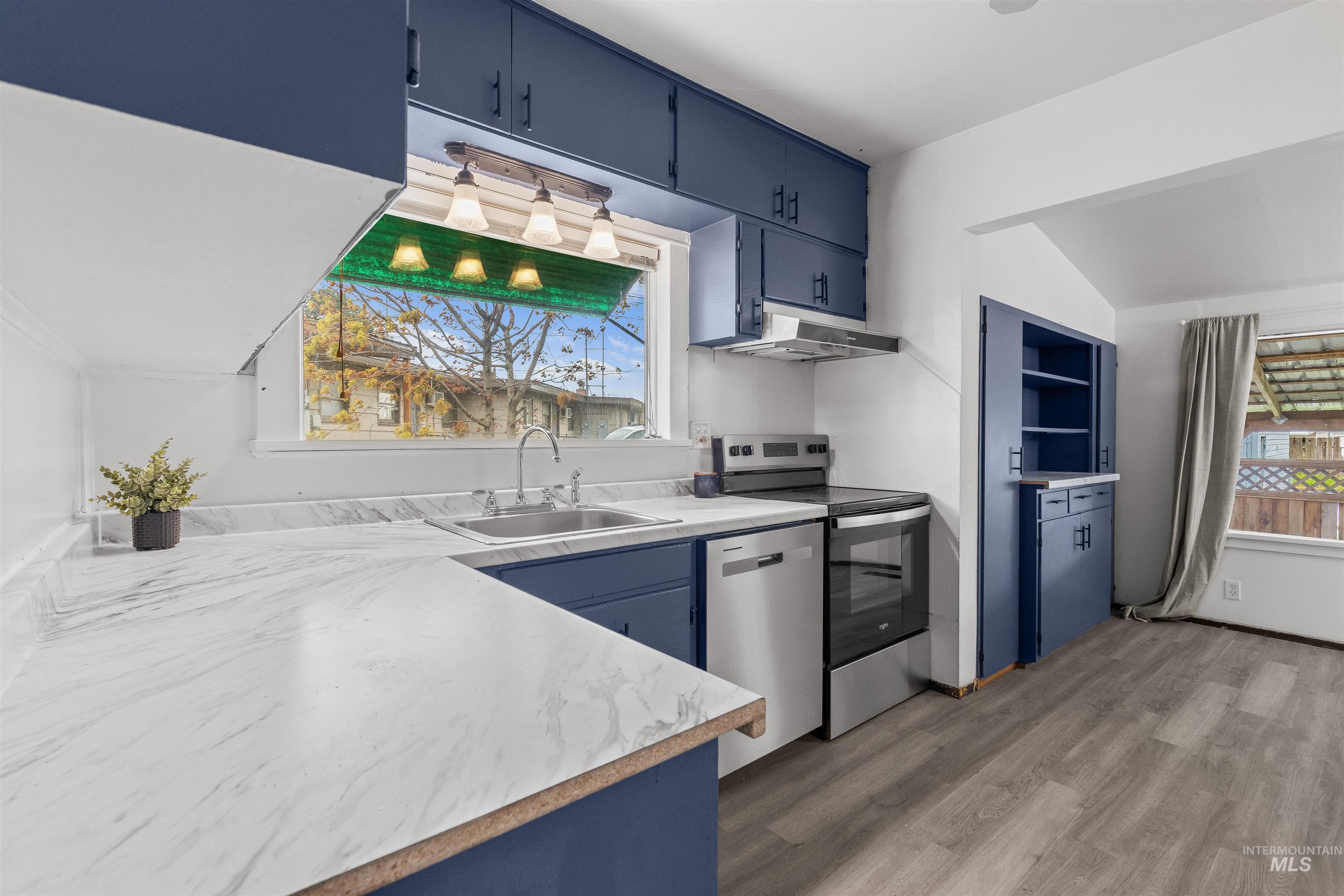 716 7th Street Clarkston, WA 99403 - Photo 7 of 38 Kitchen featuring blue cabinetry, light countertops, stainless steel appliances, light wood-style flooring, and lofted ceiling