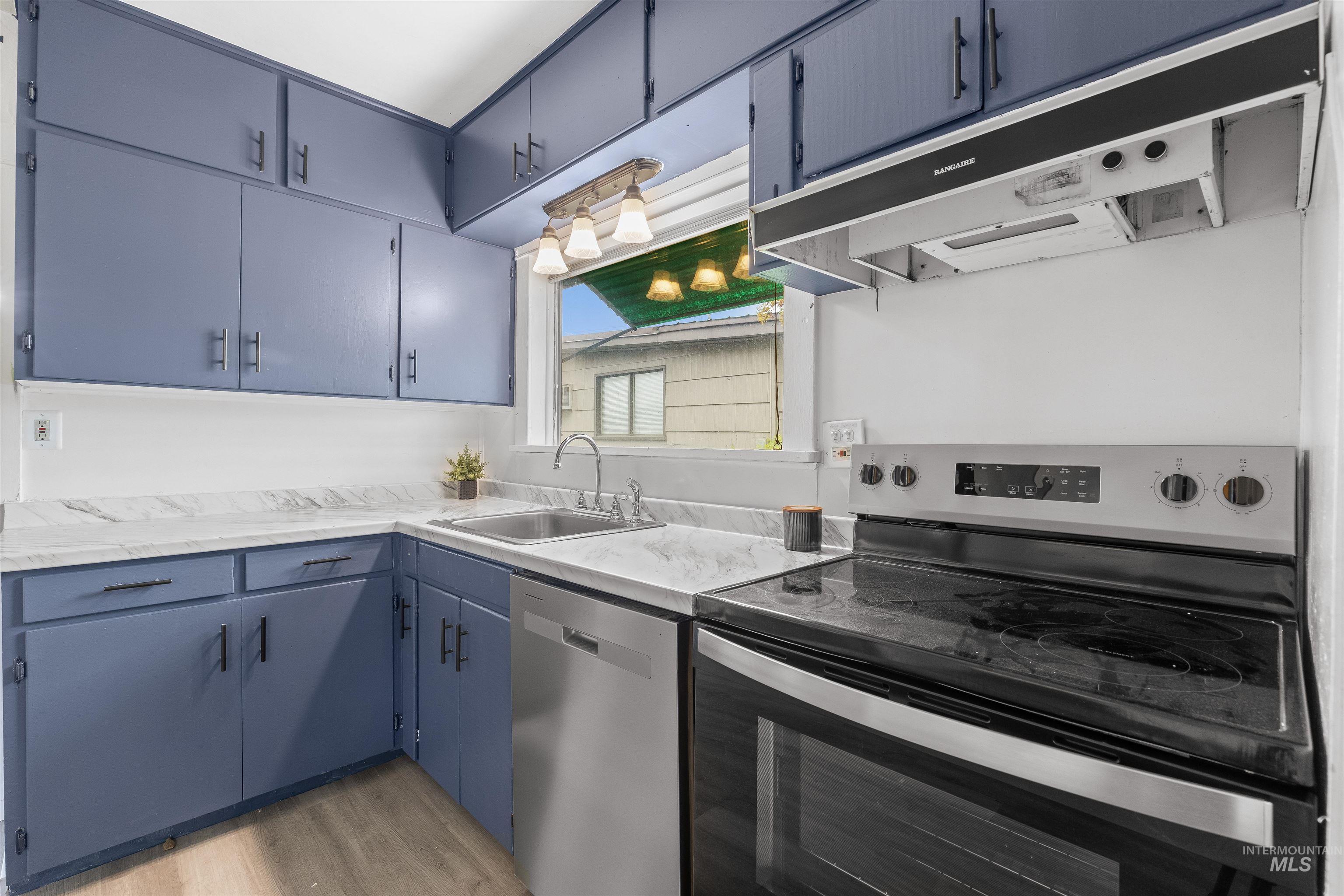 716 7th Street Clarkston, WA 99403 - Photo 9 of 38 Kitchen with stainless steel appliances, blue cabinets, light countertops, and light wood-style floors