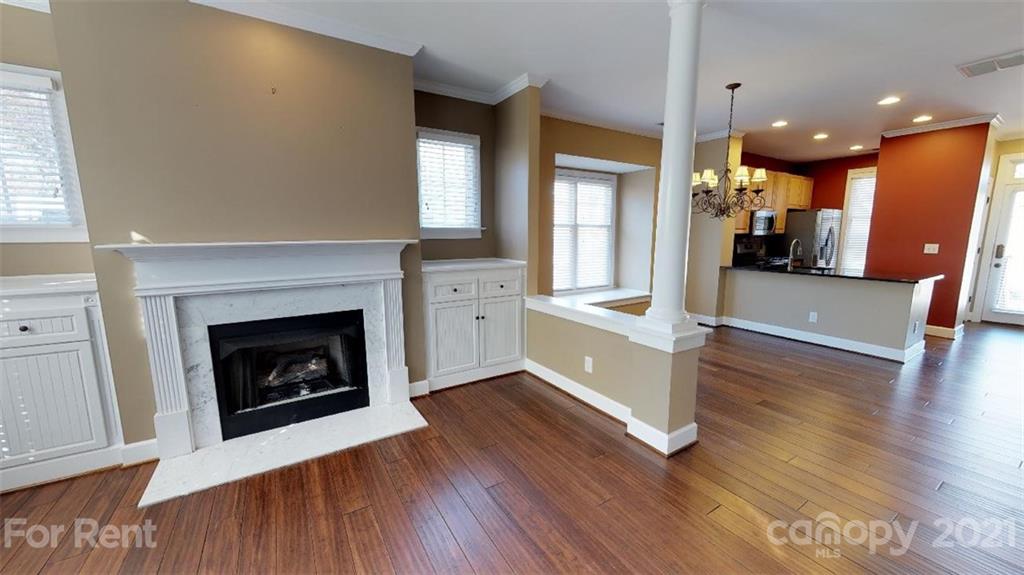 a living room with stainless steel appliances wooden floor and a fireplace