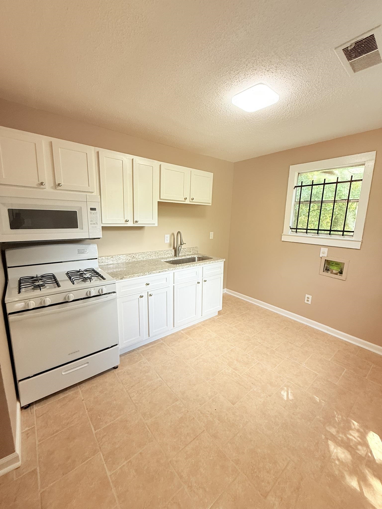 931 Calvin Road Memphis, TN 38109 - Photo 2 of 15 a kitchen with stainless steel appliances granite countertop a stove a sink and a microwave