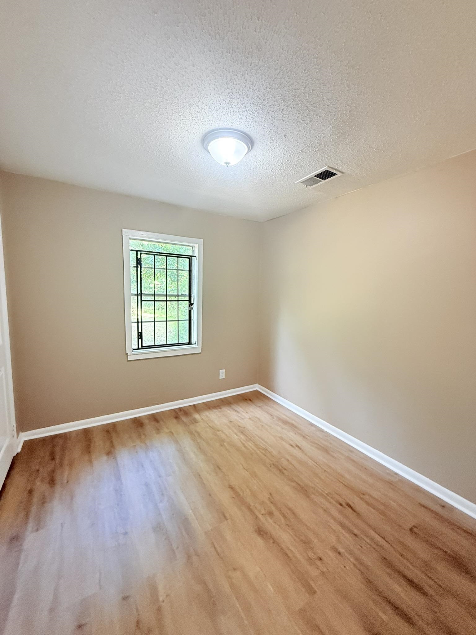 931 Calvin Road Memphis, TN 38109 - Photo 9 of 15 an empty room with wooden floor and windows