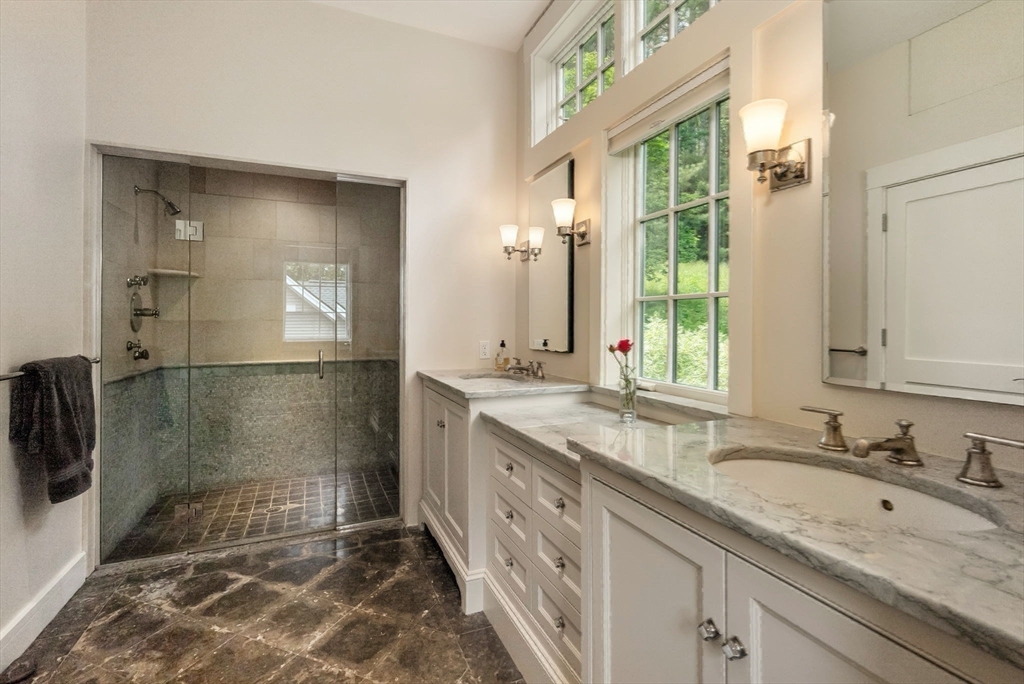 61 Dutton Road Sudbury, MA 01776 - Photo 32 of 42 a bathroom with a granite countertop sink a mirror and a shower