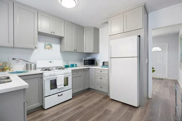 a kitchen with cabinets appliances wooden floor and a window