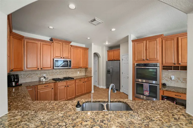 a kitchen with stainless steel appliances granite countertop a sink a stove and a refrigerator