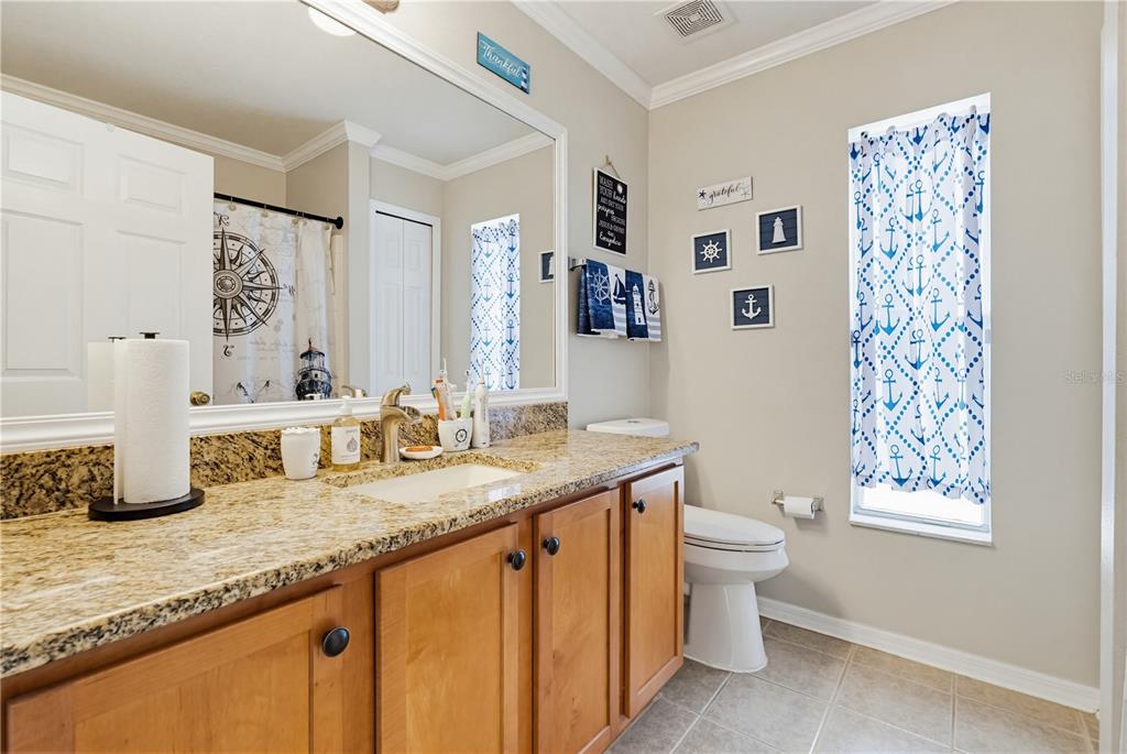 3497 Chadwick Avenue Spring Hill, FL 34609 - Photo 33 of 47 a bathroom with double vanity sink a mirror a toilet and a window