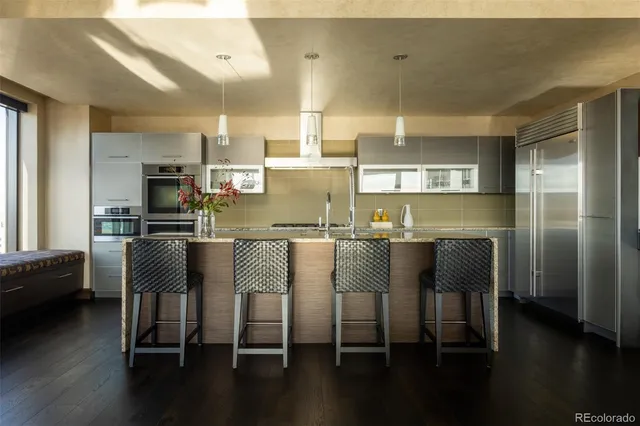 a view of kitchen with stainless steel appliances granite countertop dining table chairs and a wooden floor