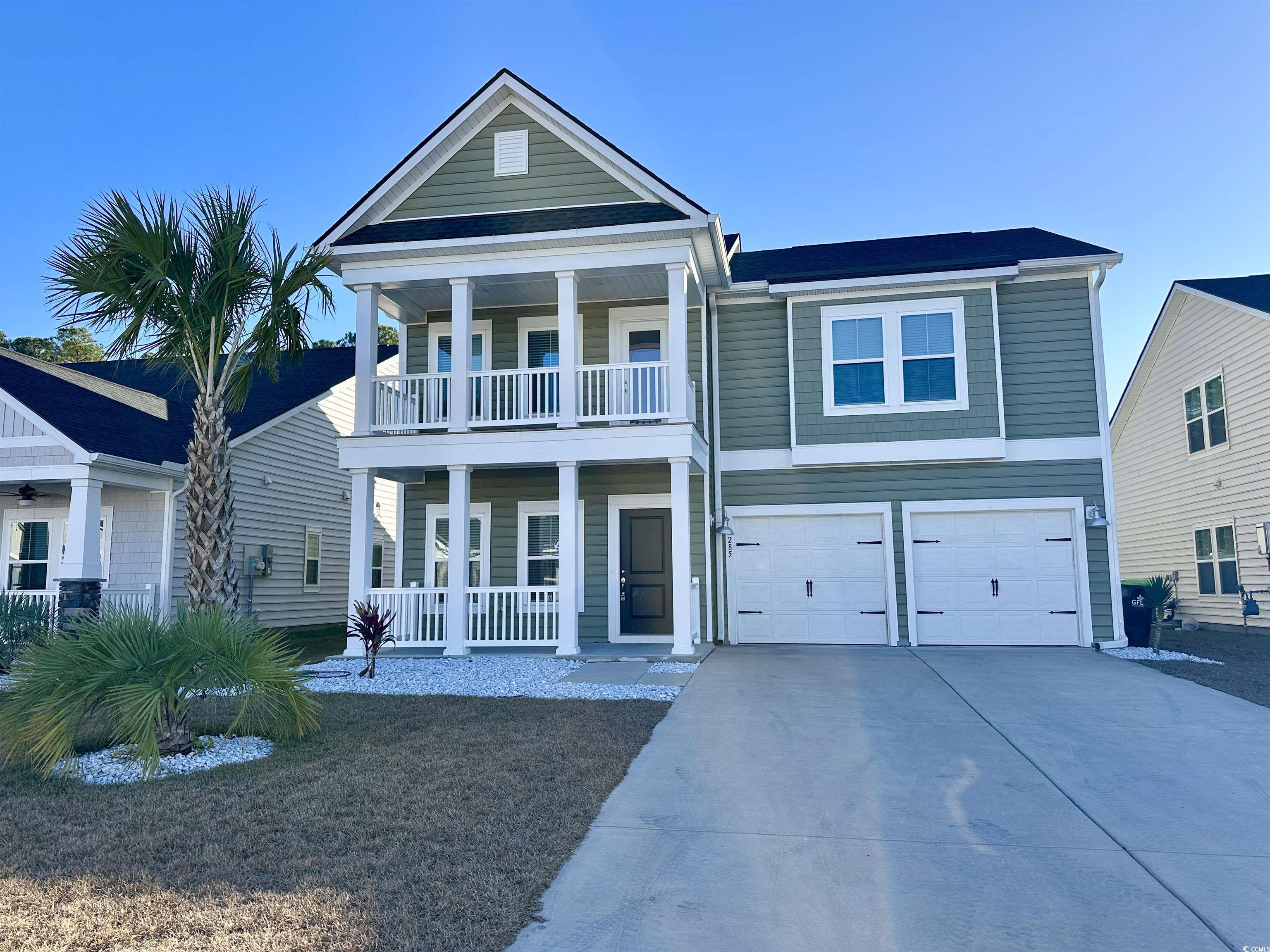 View of front facade featuring covered porch, driveway, and a garage