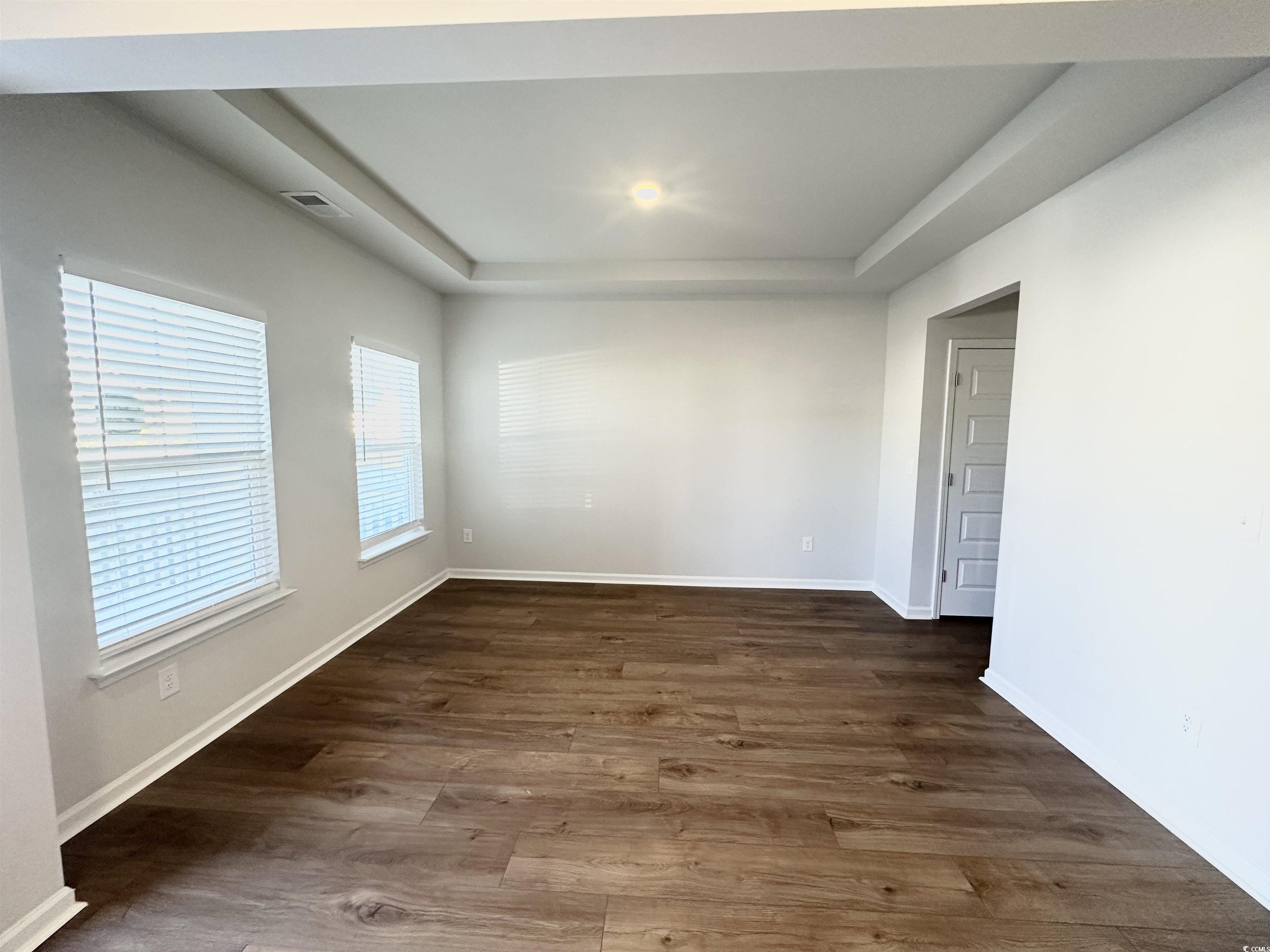 285 Augusta Grn Way Myrtle Beach, SC 29579 - Photo 3 of 28 Empty room with a tray ceiling and dark wood-style floors