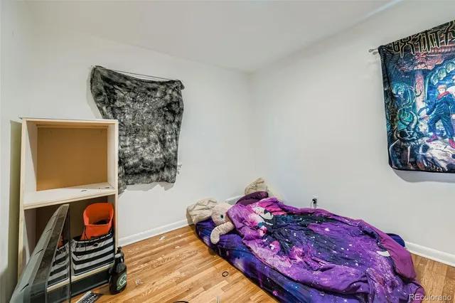 a bed room with a bed a wall painting and a lamp