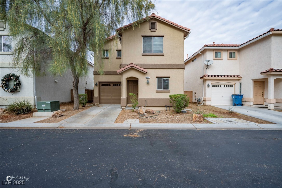 Mediterranean / spanish-style house with stucco siding, concrete driveway, a tiled roof, and a garage