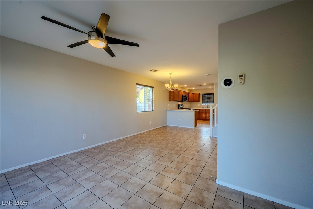 5283 Broadlake Lane Las Vegas, NV 89122 - Photo 27 of 36 Unfurnished living room featuring light tile patterned floors, ceiling fan, and a chandelier